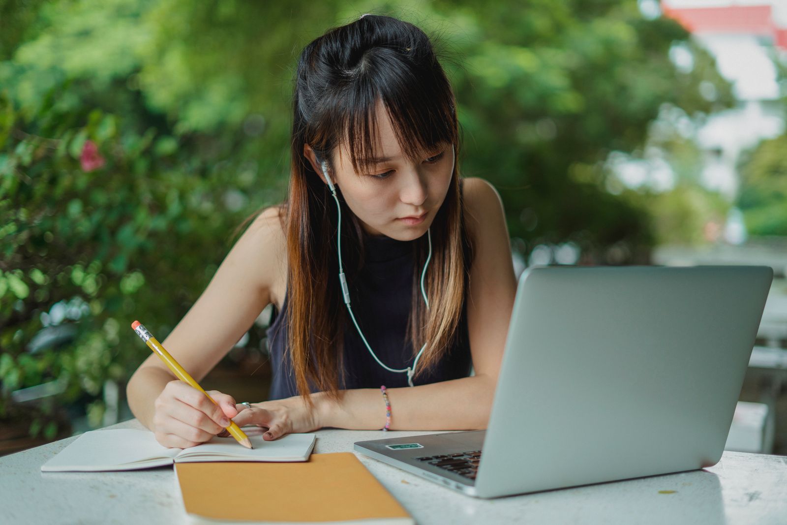Asian learner taking notes during an online lesson